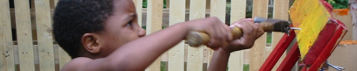 Jongen slaat met een hamer een spijker in een houten pallet