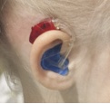 Kinderoor met kleurrijk hoorapparaat in en aan het oor.